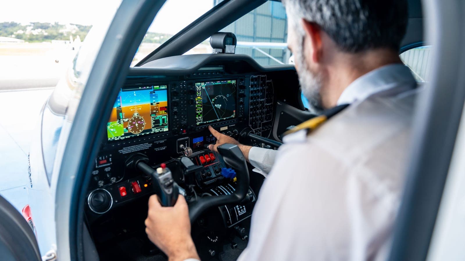 A pilot reaching out to touch a glass cockpit display showing a moving map in a light aircraft