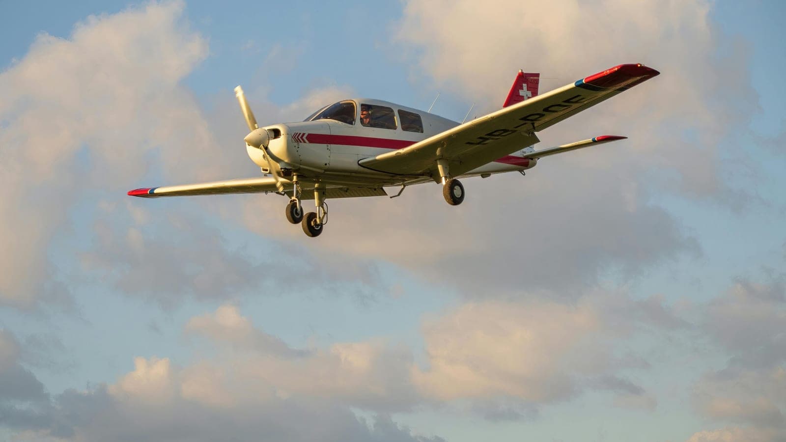 A Piper in flight against a bank of late afternoon cloud